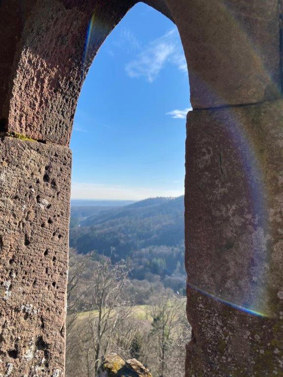 Vue à travers une arcade du château du Vieux Windstein sur les collines boisées