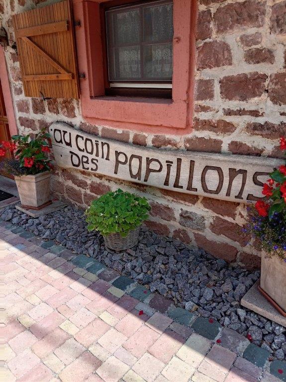 Enseigne en bois gravée « Au coin des papillons » et fleurs devant la bergerie