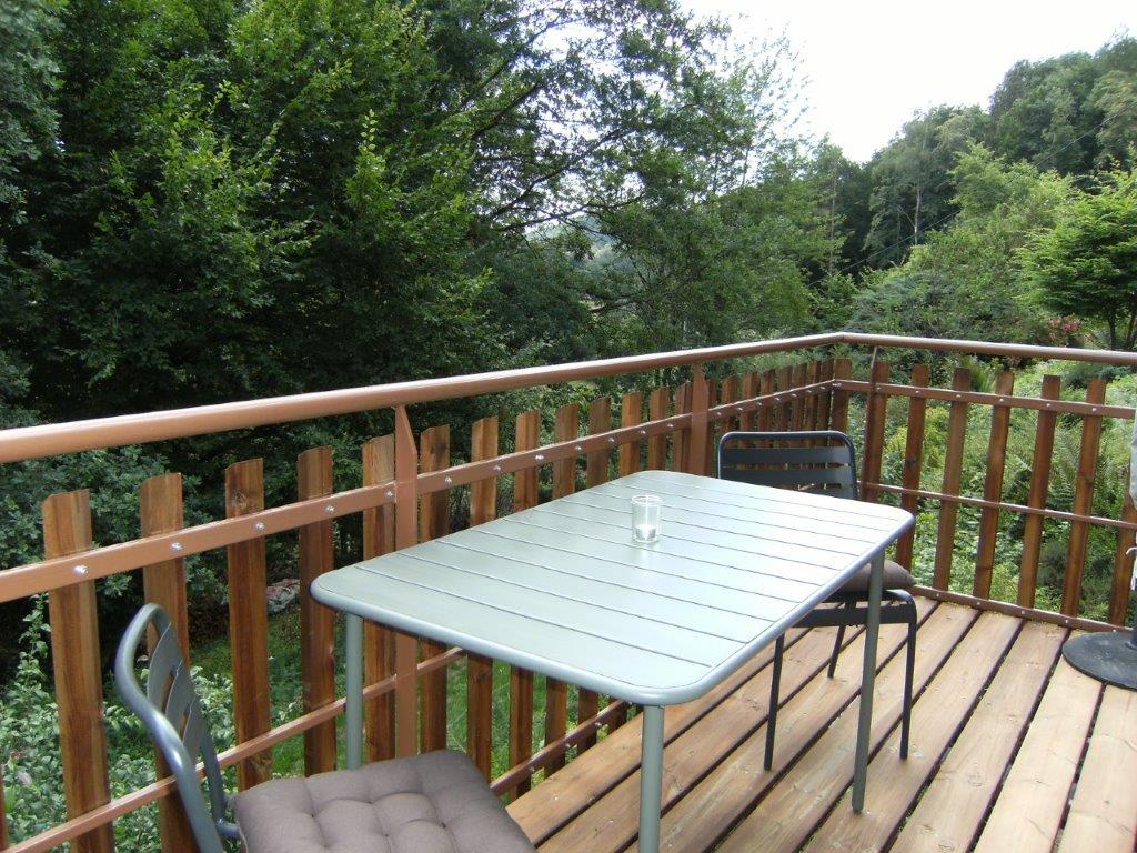 Balcon en bois avec table, chaises et vue sur la forêt
