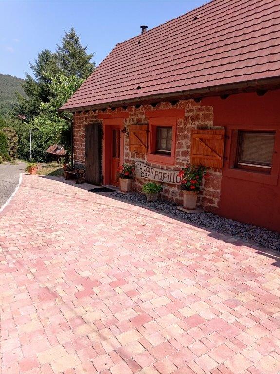 Façade en grès rose du gîte Au coin des papillons à Windstein avec sa cour pavée